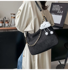 Detail of black corduroy tote with gold chain and white plush cloud charm on side
