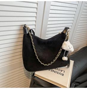 Detail of black suede hobo bag with gold chain strap and fluffy cloud charm accessory