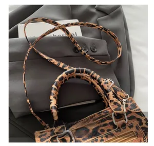 Close-up of leopard print handbag with silver hardware details on gray suit jacket