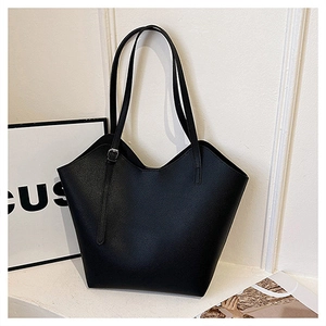 Detail of black pebbled faux leather tote bag showing unique wavy top edge and slim strap