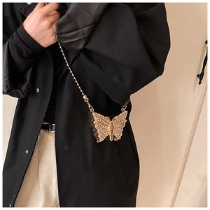 Detalle del bolso de fiesta mariposa dorada con textura de pedrería y cadena fina