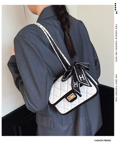 Close-up of white quilted leather bag with black trim and gold twist lock mechanism