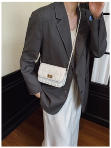 Model wearing a white quilted crossbody bag with gold chain strap and turn-lock closure