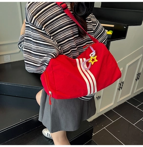 Red nylon duffel bag with white stripes and star charm detail shown in use