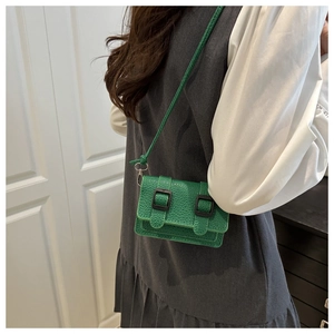 Dettaglio macro della mini borsa a tracolla verde brillante con pelle martellata e doppia fibbia