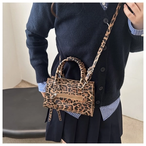 Detail of leopard print crossbody bag with tassel and adjustable strap on model