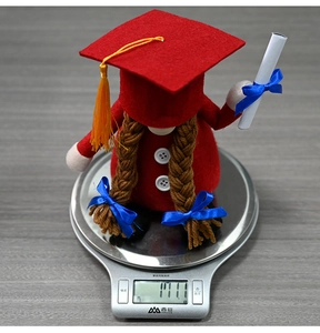 Close-up of a graduation gnome plush with red mortarboard hat and tiny diploma scroll