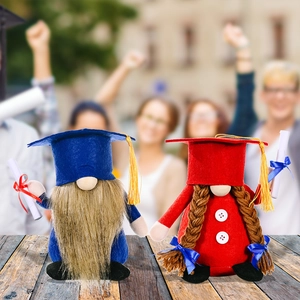 Pair of blue and red graduation gnomes with mortarboard hats and scrolls on wood surface