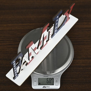 Macro view showing the lightweight 68.7g wooden FAMILY sign on a digital scale