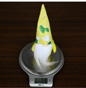 Detailed view of lemon pattern gnome doll weighing 54.0g on a kitchen scale