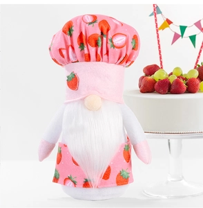 Close-up of strawberry chef gnome plush doll with pink hat next to a decorative cake