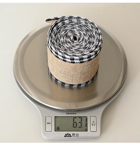 Close-up of linen style Christmas ribbon with black and white checkered edges on a scale