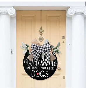 Close-up of wooden welcome sign with buffalo plaid bow and eucalyptus leaves on door