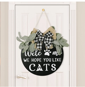 Detail of wooden welcome sign with cat silhouette, buffalo plaid bow and greenery