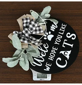 Detail of round wooden Welcome sign with cat paw prints and a plaid burlap bow decoration