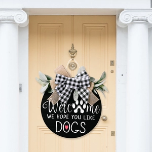 Rustic wooden Welcome We Hope You Like Dogs sign with black and white bow on a wooden door