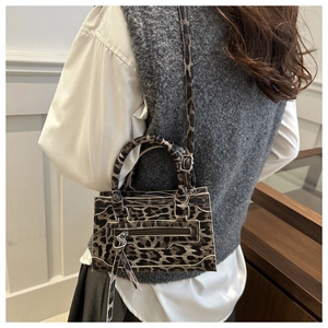 Detail of leopard print crossbody bag featuring braided handles and long leather tassels
