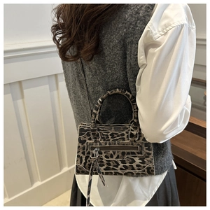 Detail view of leopard print mini handbag with white contrast piping and tassel zipper