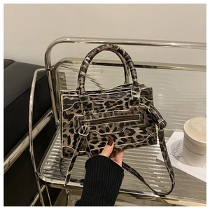 Detail of leopard print faux leather handbag with silver metal zippers and top handle
