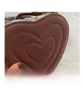 Close-up of brown heart-shaped leather bag with embossed concentric layers and gold zippers