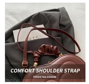 Detail of brown heart-shaped leather bag with quilted pattern and ruched cloud handle