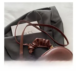 Detail of brown heart-shaped leather bag with quilted pattern and ruched cloud handle