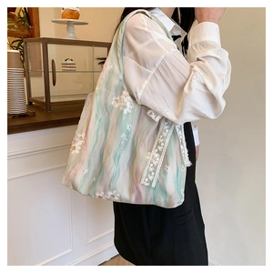 Detail of floral embroidery and lace trim on a soft aesthetic fabric tote bag