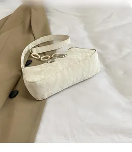 Detail of white pleated texture shoulder bag featuring silver butterfly buckle and metal chain