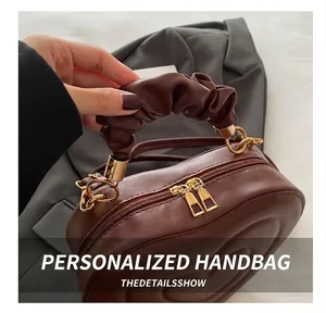 Close-up of brown heart-shaped quilted bag with ruched handle and gold double zippers