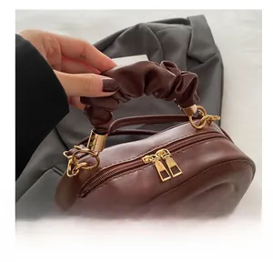Close-up of brown heart-shaped quilted bag with ruched handle and gold double zippers