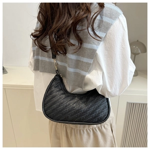 Borsa hobo intrecciata nera minimalista indossata da una modella in un interno