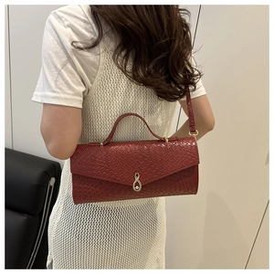 Gros plan d'un sac à main bordeaux avec texture tressée et fermoir doré en huit