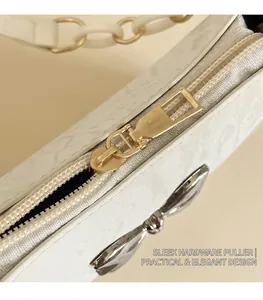 Detailed macro view of the smooth gold metal zipper puller on a white textured bag