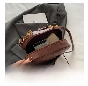 Macro view of dark brown PU leather crossbody bag showing internal storage capacity