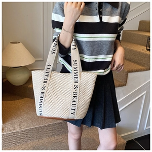 Detailed close-up of woven tote bag with 'SUMMER & BEAUTY' strap and leather base