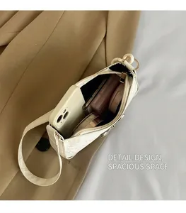 Detail view of the spacious white underarm bag showing interior capacity and golden zipper