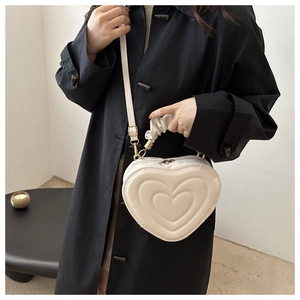Detail of a beige heart-shaped bag with layered quilting and a unique ruched handle strap