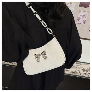 Detail of white underarm bag with glossy pleated texture and silver metal bow ornament