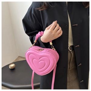 Detailed view of a pink heart-shaped bag with pleated handle and golden double zippers