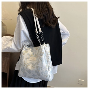 Vue détaillée du sac cabas blanc à motif papillon avec chaîne argentée et bandoulière cuir