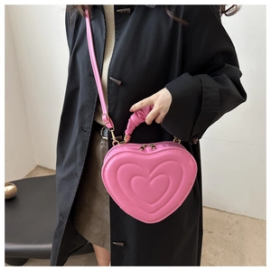 Detail of pink heart-shaped handbag featuring embossed texture and pleated handle