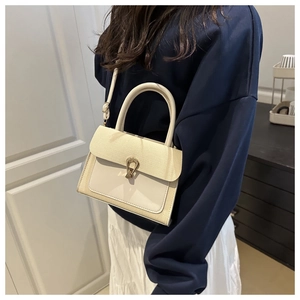 Detail of cream woven handbag with gold horseshoe buckle on model in home setting