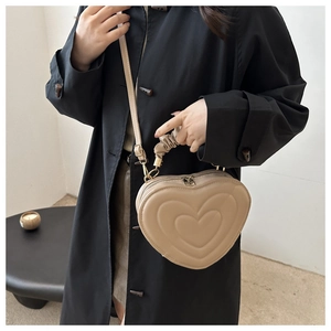 Detail of a khaki heart-shaped handbag with pleated handle and golden zipper hardware