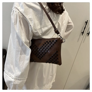 Detail of vintage brown shoulder bag featuring black studded V-shaped rivets and silver hooks