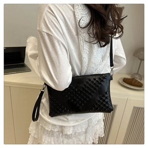 Detailed close-up of a black leather crossbody bag featuring geometric rivet decoration