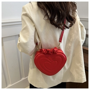 Detail of red heart-shaped shoulder bag featuring ruffle trim and gold metal hardware