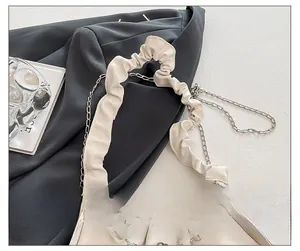 Détail de la bandoulière en satin plissé blanc avec chaîne argentée et breloques en perles