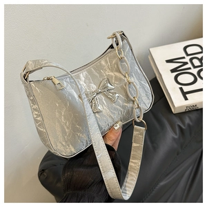 Detailed view of silver metallic shoulder bag featuring a decorative bow and chain