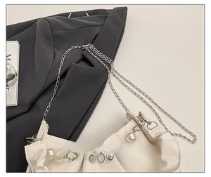 Détail du sac froncé blanc avec chaîne argentée et pendentifs fleurs en perles