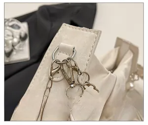 Détail d'un sac en cuir crème avec des boucles dorées et une bandoulière de perles
